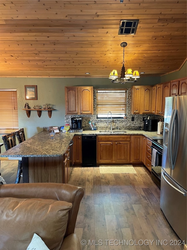 kitchen featuring appliances with stainless steel finishes, an inviting chandelier, wood-type flooring, pendant lighting, and sink