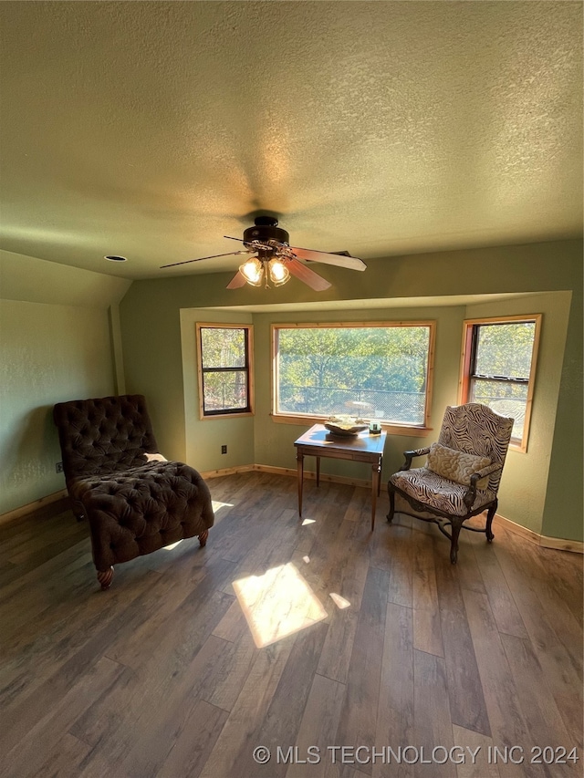 sitting room with lofted ceiling, hardwood / wood-style floors, a textured ceiling, and plenty of natural light