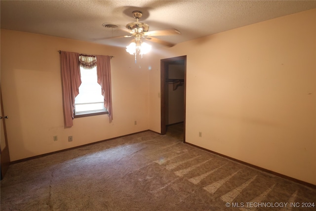 unfurnished bedroom with a walk in closet, a textured ceiling, and carpet flooring