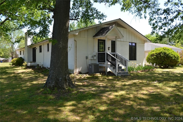 view of front facade with cooling unit and a front lawn