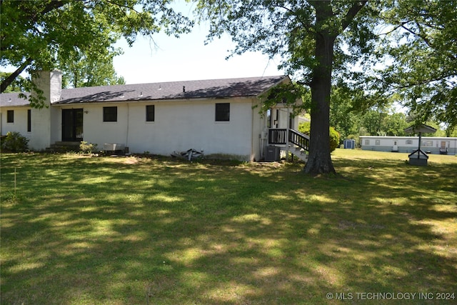 back of house featuring central AC and a lawn