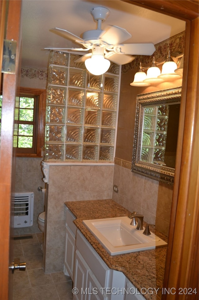 bathroom with toilet, tile patterned flooring, vanity, heating unit, and tile walls