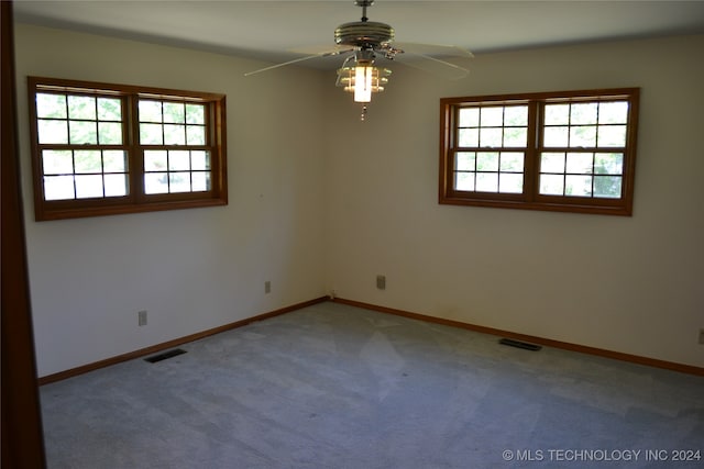 carpeted spare room featuring a wealth of natural light and ceiling fan