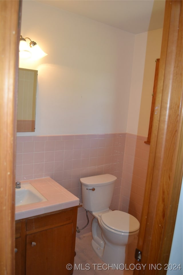 bathroom featuring vanity, toilet, and tile walls