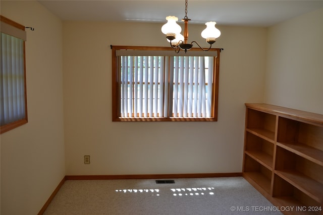 carpeted empty room featuring a chandelier