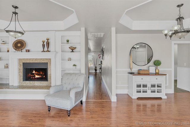 living area with built in features, wood-type flooring, and a high end fireplace