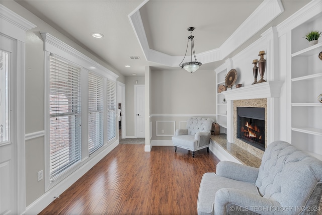 living area with a premium fireplace, built in shelves, and dark hardwood / wood-style flooring