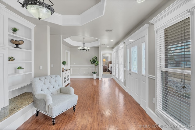 entryway featuring a notable chandelier, a healthy amount of sunlight, a tray ceiling, and hardwood / wood-style floors