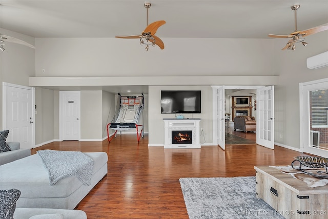 living room with a towering ceiling, a wall unit AC, dark hardwood / wood-style floors, and ceiling fan