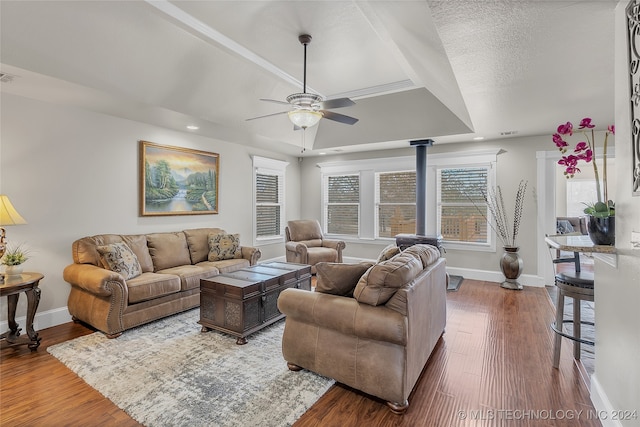 living room featuring dark wood-type flooring, a tray ceiling, a textured ceiling, and ceiling fan