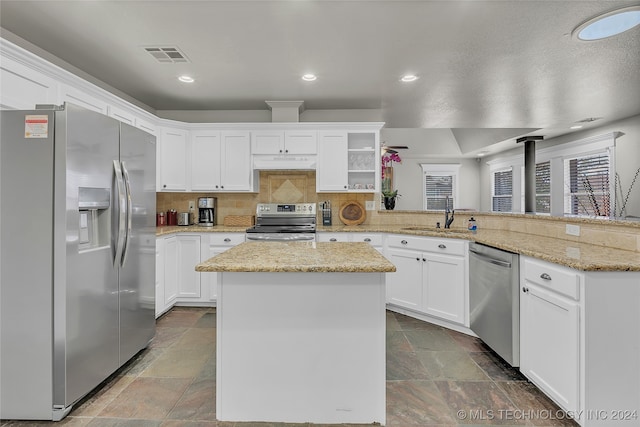 kitchen with decorative backsplash, custom range hood, kitchen peninsula, white cabinetry, and appliances with stainless steel finishes