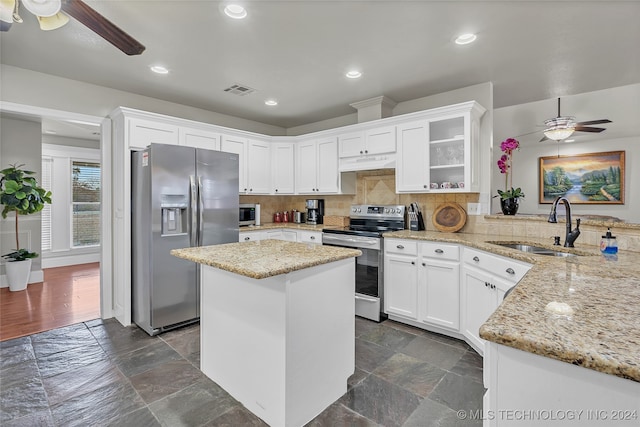 kitchen featuring kitchen peninsula, tasteful backsplash, appliances with stainless steel finishes, white cabinetry, and sink