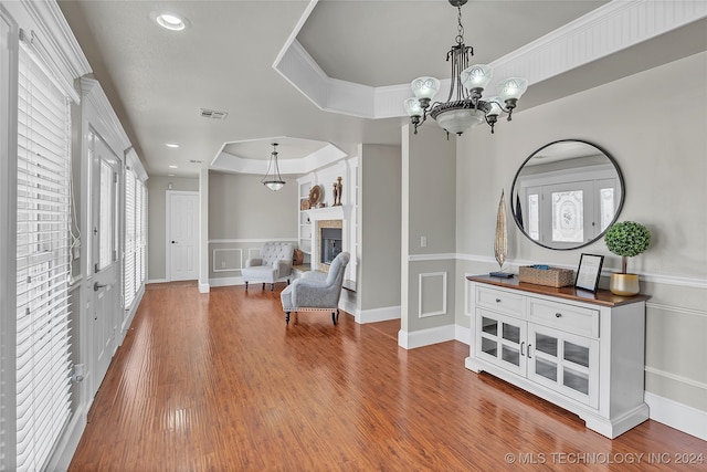 living area featuring an inviting chandelier, hardwood / wood-style flooring, and a raised ceiling