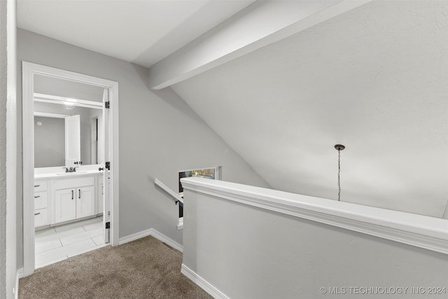 hall featuring light carpet, sink, and vaulted ceiling with beams