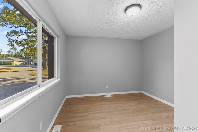 empty room with light hardwood / wood-style flooring and a textured ceiling