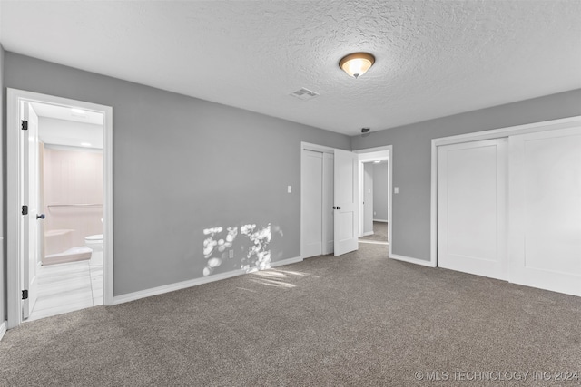 unfurnished bedroom featuring connected bathroom, carpet, and a textured ceiling