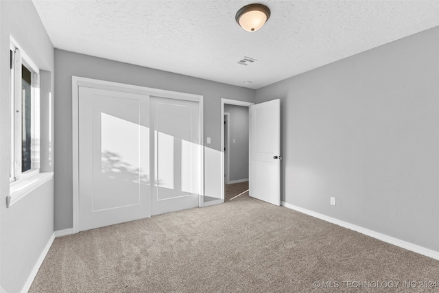 unfurnished bedroom with a closet, carpet, and a textured ceiling