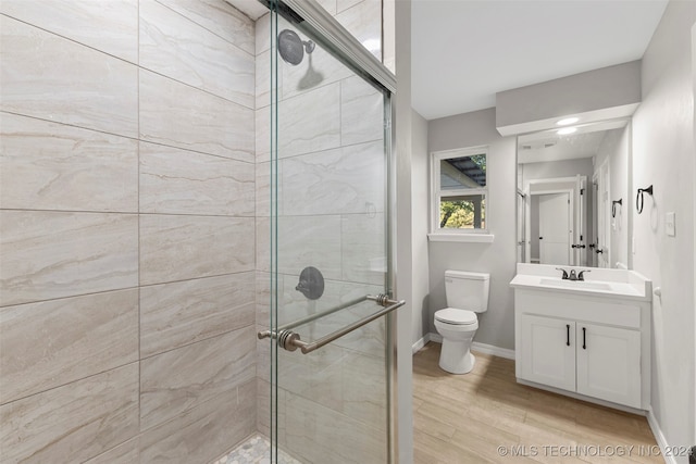 bathroom with toilet, hardwood / wood-style floors, walk in shower, and vanity