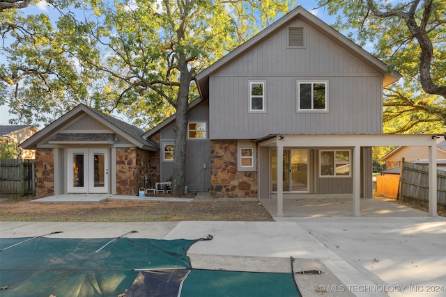 back of property featuring french doors, a patio area, and a covered pool