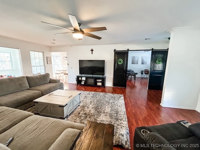 living room featuring ceiling fan, a barn door, and dark hardwood / wood-style flooring