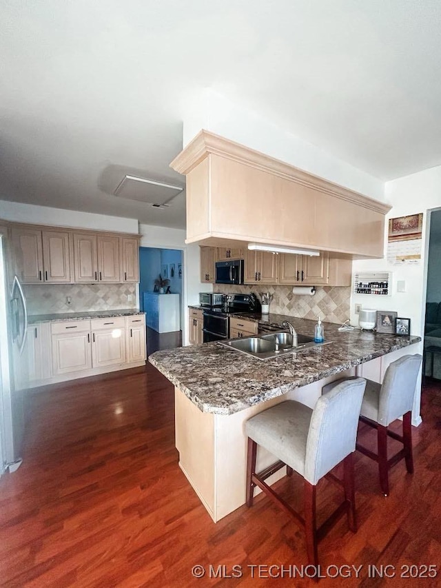 kitchen featuring dark wood-type flooring, sink, stainless steel refrigerator, kitchen peninsula, and range with two ovens