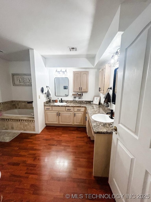 bathroom with vanity, hardwood / wood-style floors, and tiled tub