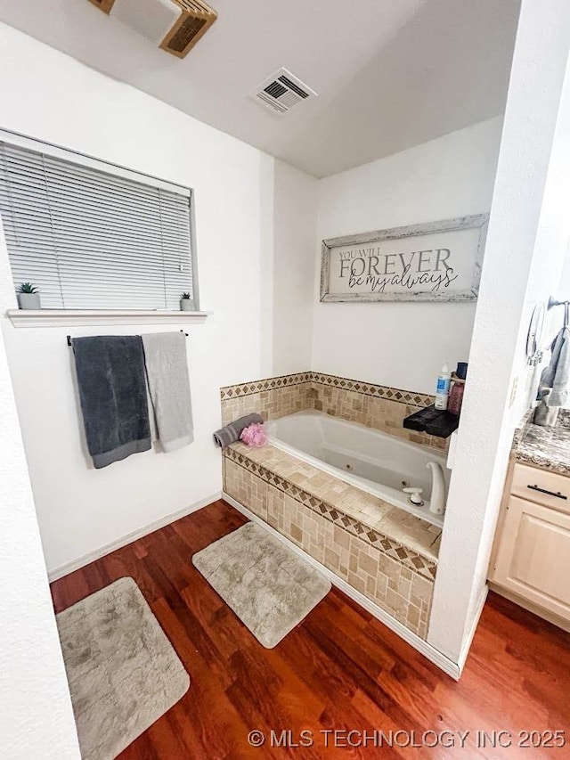 bathroom featuring vanity, hardwood / wood-style floors, and tiled tub