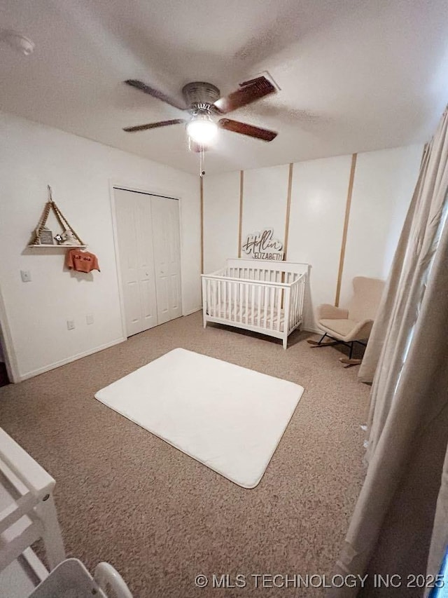 carpeted bedroom featuring ceiling fan, a closet, and a crib