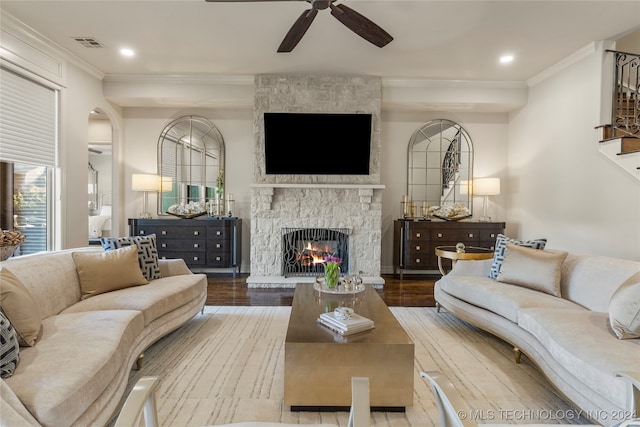 living room featuring crown molding, hardwood / wood-style floors, a fireplace, and ceiling fan