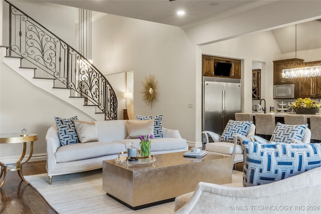 living room featuring ornamental molding, a chandelier, vaulted ceiling, and light hardwood / wood-style floors