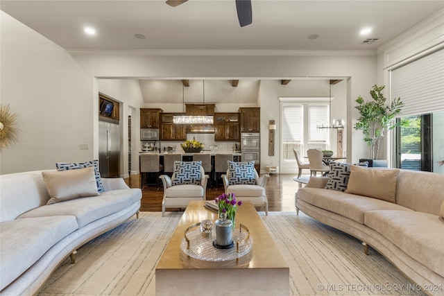 living room with crown molding, ceiling fan with notable chandelier, and light wood-type flooring