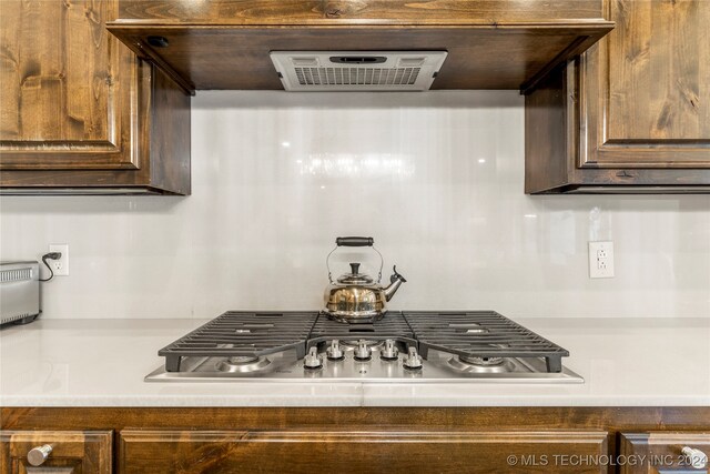 kitchen featuring range hood, stainless steel gas cooktop, and dark brown cabinets