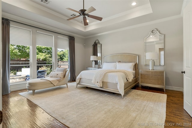 bedroom featuring hardwood / wood-style floors, crown molding, a tray ceiling, and ceiling fan