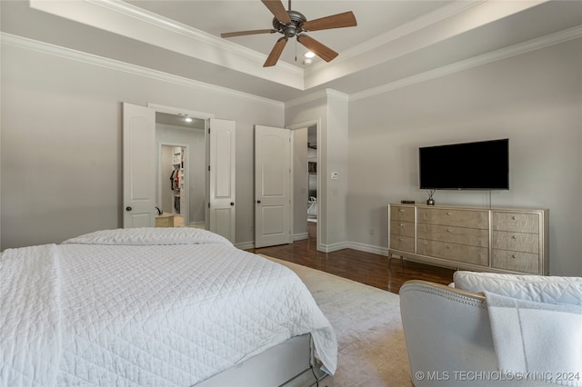 bedroom featuring crown molding, hardwood / wood-style floors, a tray ceiling, and ceiling fan