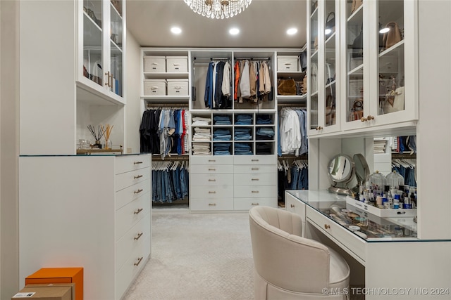 walk in closet featuring a notable chandelier and light carpet