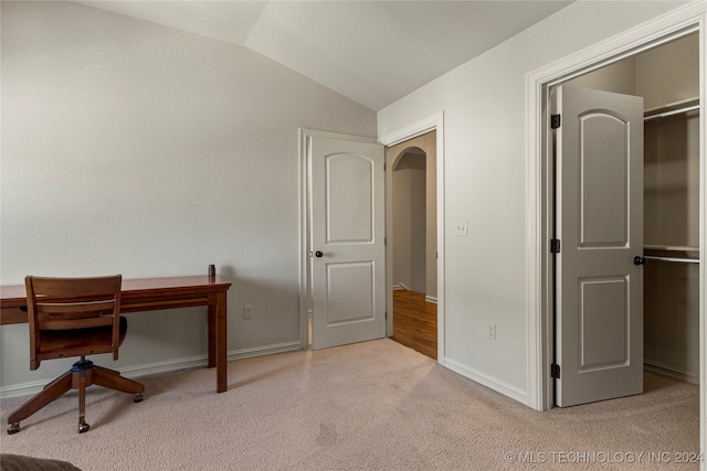 office space with built in desk, vaulted ceiling, and light colored carpet