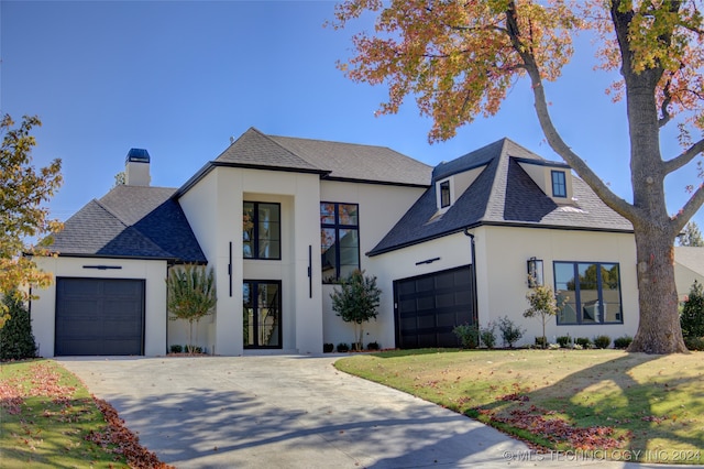 french country inspired facade featuring a garage and a front yard