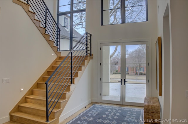 entrance foyer featuring french doors, a towering ceiling, and a wealth of natural light