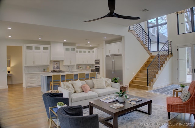 living room featuring ceiling fan, light wood-type flooring, and sink