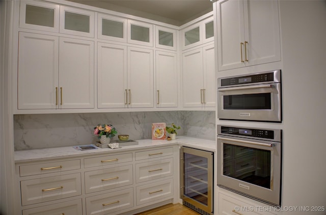 kitchen featuring white cabinets, double oven, backsplash, and wine cooler