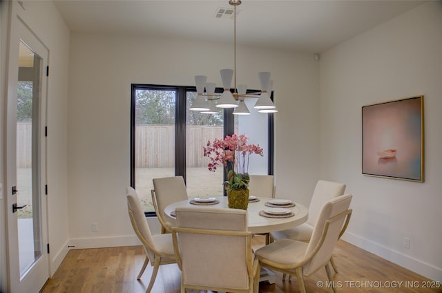 dining room featuring light wood-type flooring and an inviting chandelier