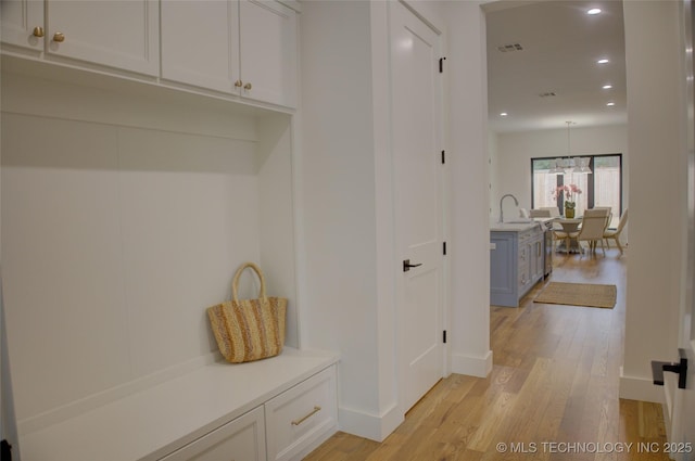 mudroom featuring light wood-type flooring, an inviting chandelier, and sink