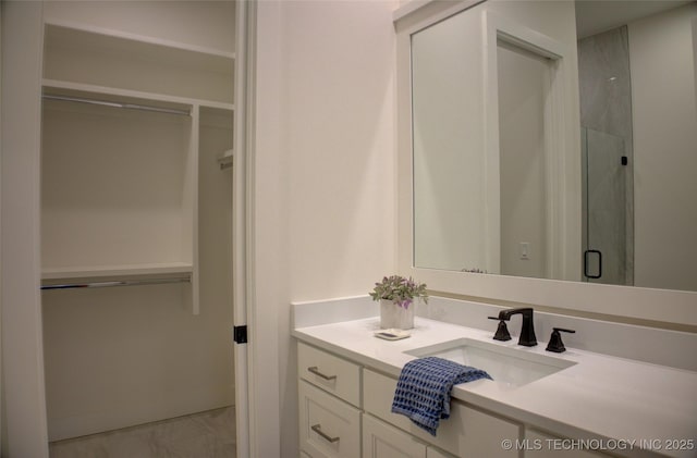 bathroom featuring a shower with door and vanity