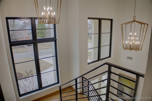 stairs featuring hardwood / wood-style floors and a notable chandelier