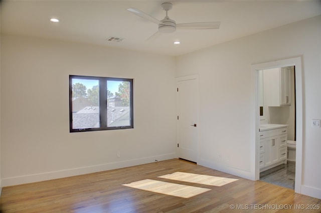 unfurnished bedroom featuring ensuite bathroom, light hardwood / wood-style flooring, and ceiling fan