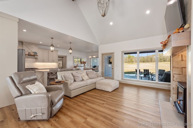 living room with high vaulted ceiling, light wood-type flooring, and sink