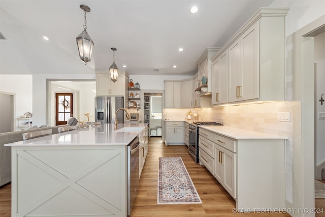 kitchen with stainless steel appliances, sink, decorative light fixtures, a spacious island, and light wood-type flooring