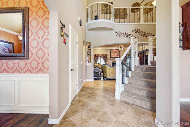 entrance foyer featuring ornamental molding, light hardwood / wood-style flooring, and a towering ceiling