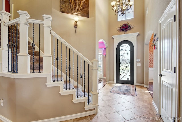 entrance foyer with a notable chandelier, light tile patterned flooring, and a high ceiling