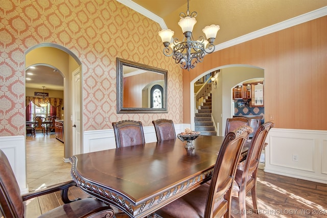 dining space featuring crown molding, wood-type flooring, lofted ceiling, and a chandelier